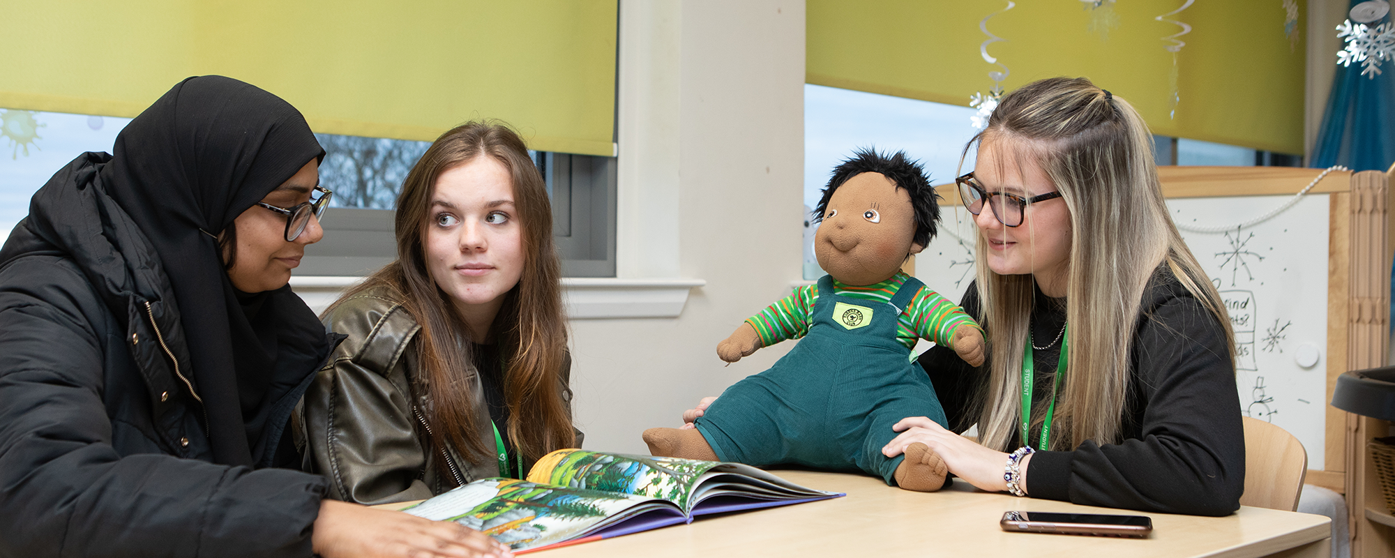 Three students reading and using puppet in a classroom. 