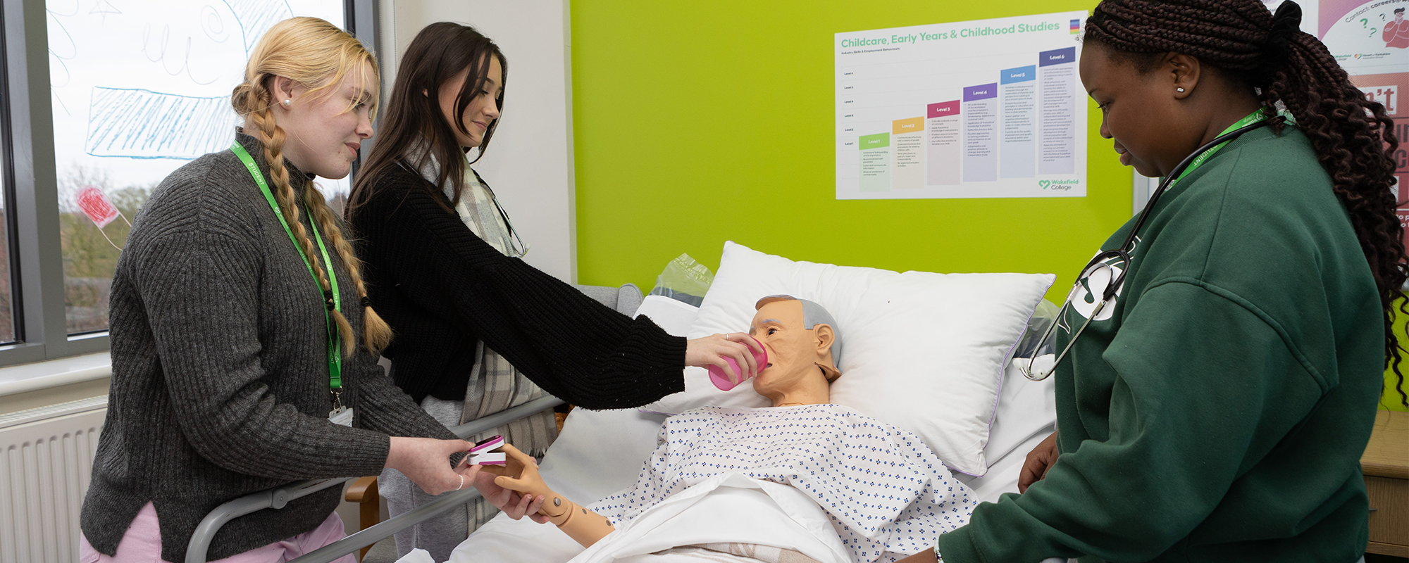 Three students treating a patient dummy in the simulation hospital ward