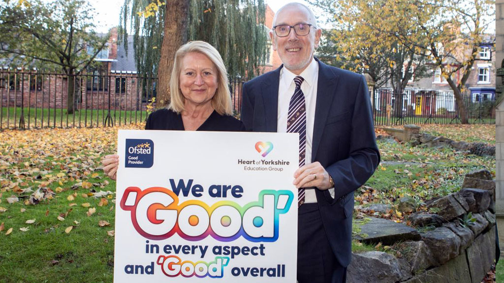 Two people holding up Ofsted sign 