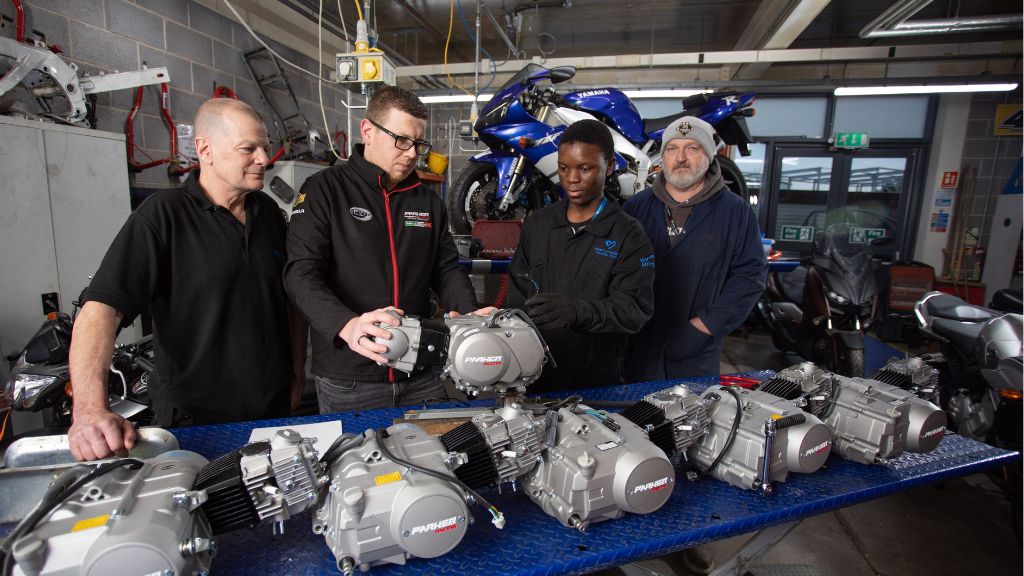 Tutor Ian Smith (left) with Arron Parker (second to left), Automotive student and Inclusion Practitioner Philip Evans (right) with the engines