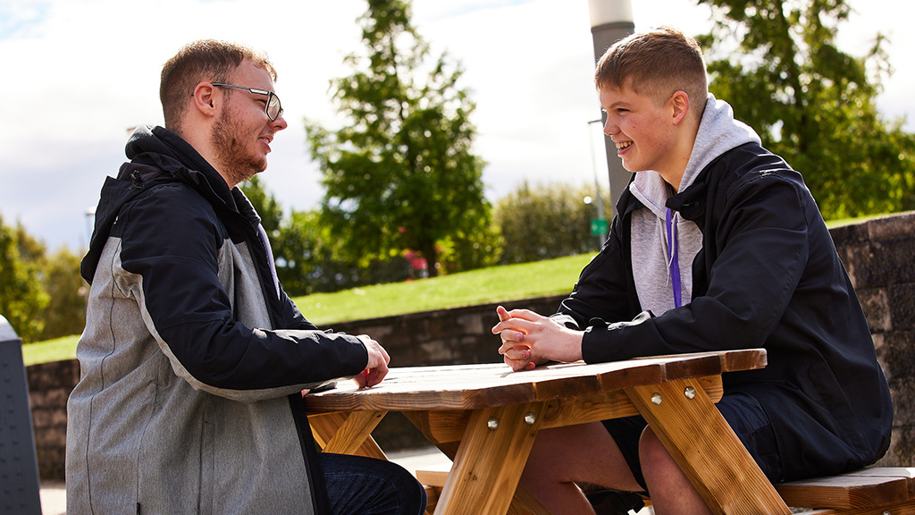 Two people speaking on bench