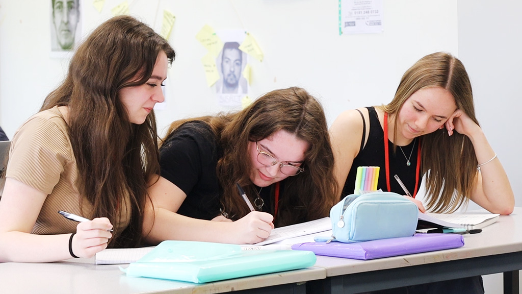 Three female students working together in a classroom 