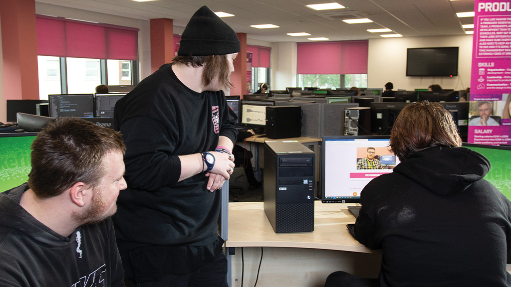 Three games development students around a computer together