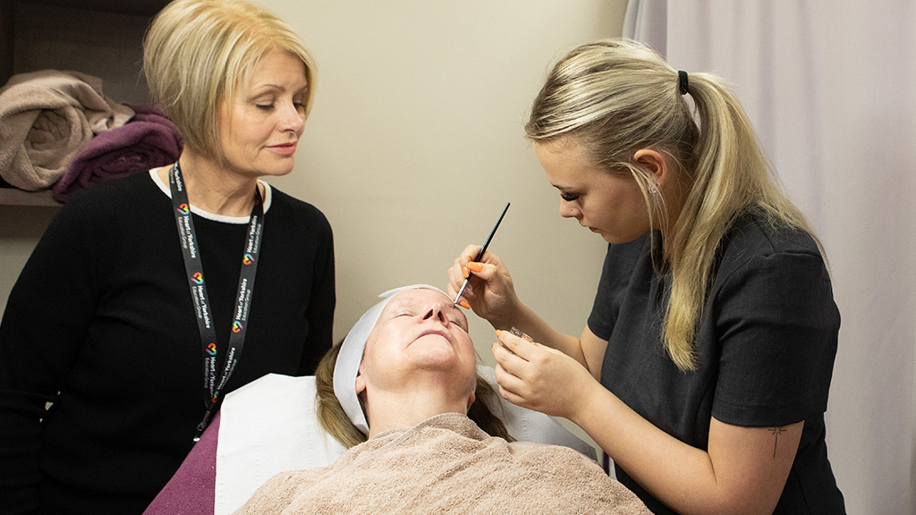 Student overseen by tutor whilst carrying out beauty treatment