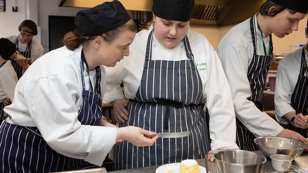 Tutor helping a student prepare a dessert in the kitchen