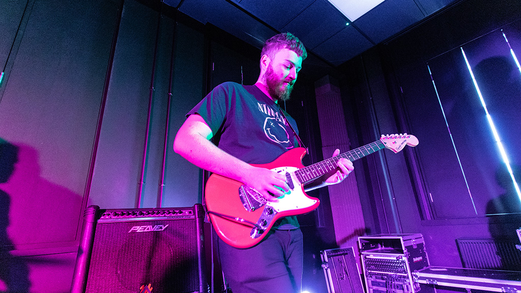 Student playing a guitar on stage